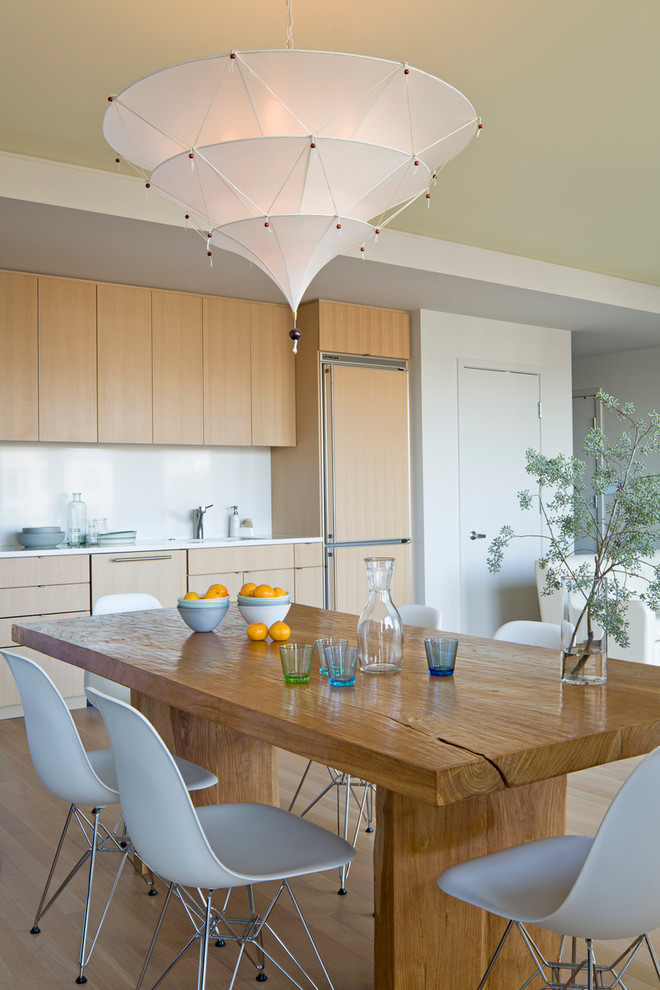 Modern eat-in kitchen in Portland with flat-panel cabinets, light wood cabinets, white splashback, glass sheet splashback and panelled appliances.