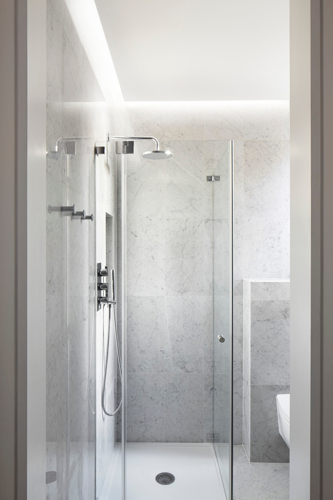 Inspiration for a small contemporary master bathroom in London with flat-panel cabinets, white cabinets, a curbless shower, a wall-mount toilet, white tile, porcelain tile, white walls, marble floors, a console sink and marble benchtops.