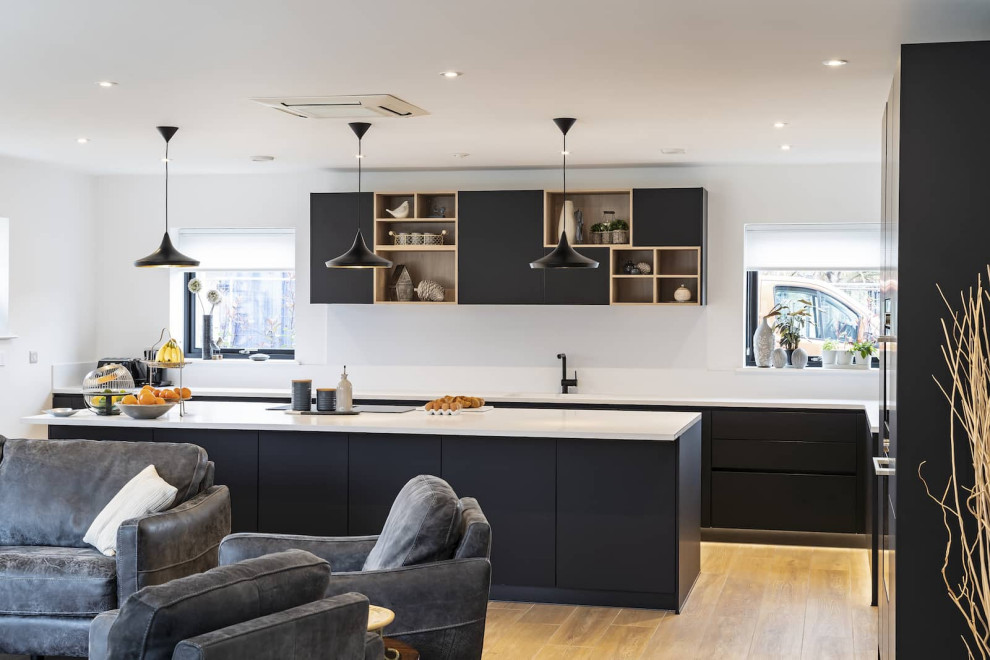 Design ideas for a large scandinavian l-shaped open plan kitchen in Oxfordshire with flat-panel cabinets, black cabinets, quartz worktops, white splashback, black appliances, light hardwood flooring, an island, brown floors, yellow worktops and feature lighting.