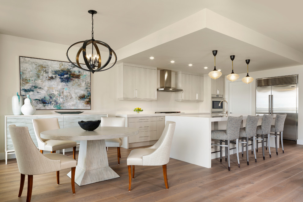 Beach style eat-in kitchen in Miami with flat-panel cabinets, light wood cabinets, beige splashback, stainless steel appliances, medium hardwood floors, with island and white benchtop.