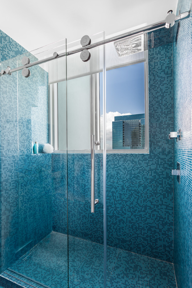 Design ideas for a mid-sized modern kids bathroom in Miami with flat-panel cabinets, white cabinets, an alcove shower, a one-piece toilet, blue tile, mosaic tile, white walls, a vessel sink and solid surface benchtops.
