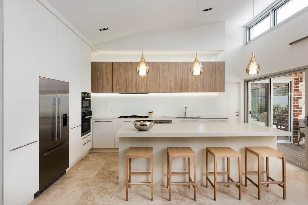This is an example of a medium sized modern l-shaped kitchen/diner in Perth with a double-bowl sink, flat-panel cabinets, white cabinets, engineered stone countertops, white splashback, engineered quartz splashback, black appliances, limestone flooring, an island, beige floors, white worktops and a vaulted ceiling.