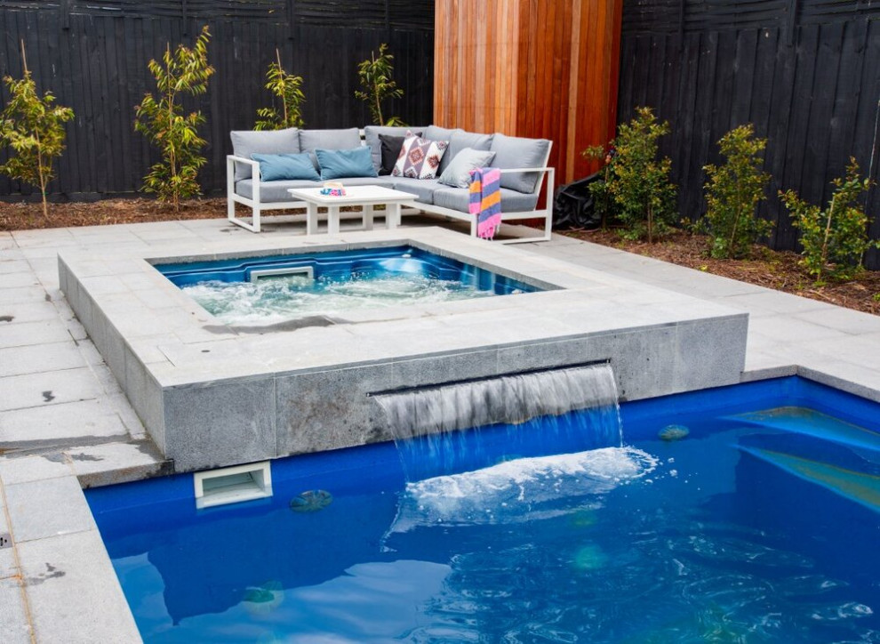 Modelo de piscina natural tradicional de tamaño medio a medida en patio trasero con paisajismo de piscina y entablado