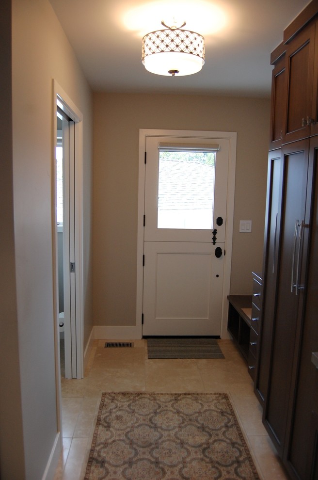 Example of a small transitional travertine floor mudroom design in Los Angeles with beige walls and a white front door
