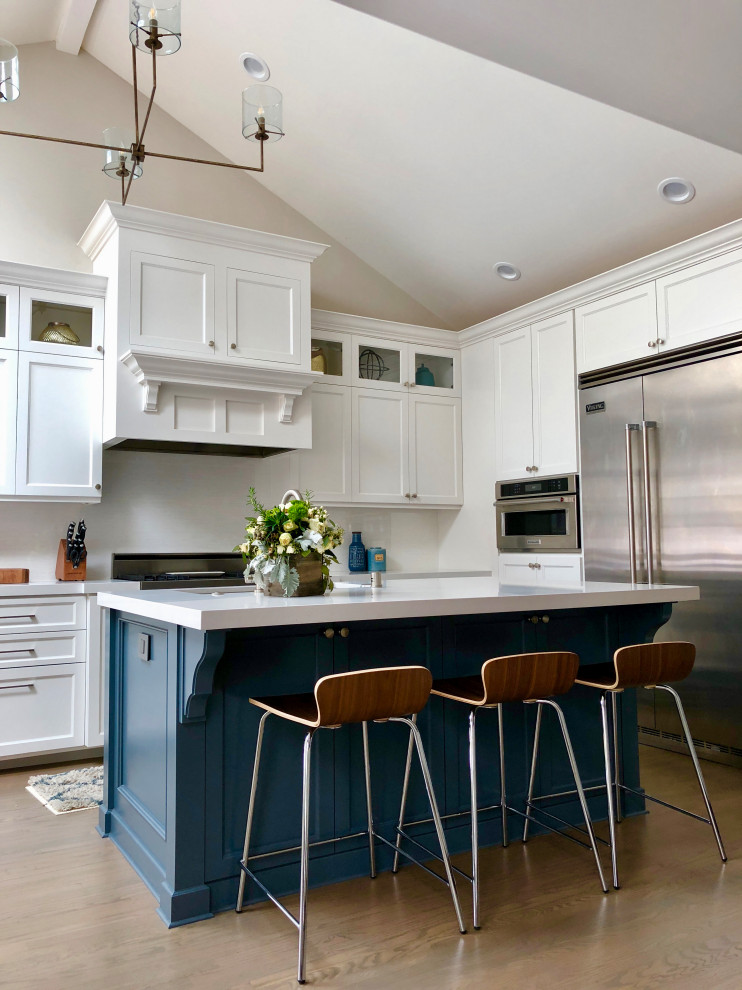 Inspiration for a transitional l-shaped kitchen in San Diego with shaker cabinets, white cabinets, stainless steel appliances, medium hardwood floors, with island, brown floor and white benchtop.