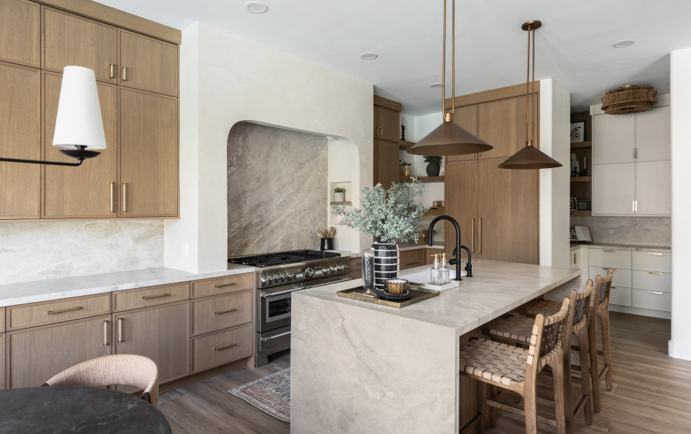 Inspiration for a transitional l-shaped medium tone wood floor and brown floor kitchen remodel in Phoenix with an undermount sink, shaker cabinets, medium tone wood cabinets, gray backsplash, stone slab backsplash, stainless steel appliances, an island and gray countertops