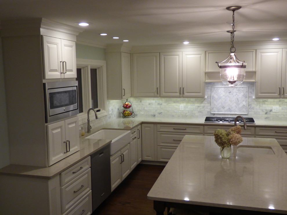 Example of a large transitional u-shaped dark wood floor eat-in kitchen design in Chicago with a farmhouse sink, raised-panel cabinets, white cabinets, quartz countertops, gray backsplash, stone tile backsplash, stainless steel appliances and an island