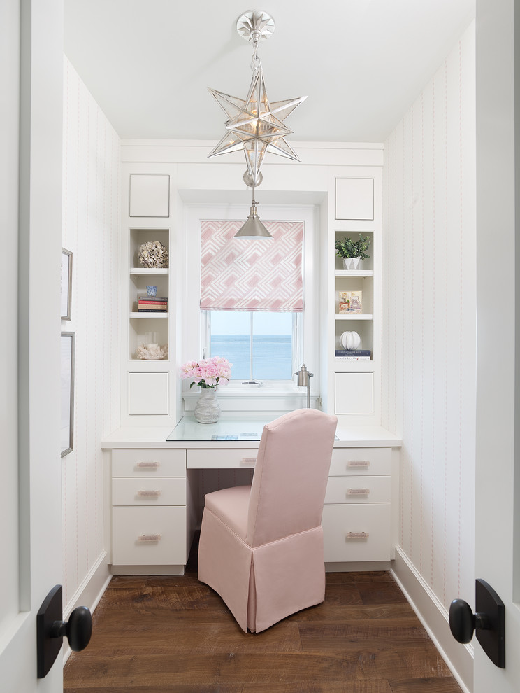 Beach style home office in Charleston with white walls, dark hardwood floors, a built-in desk and brown floor.