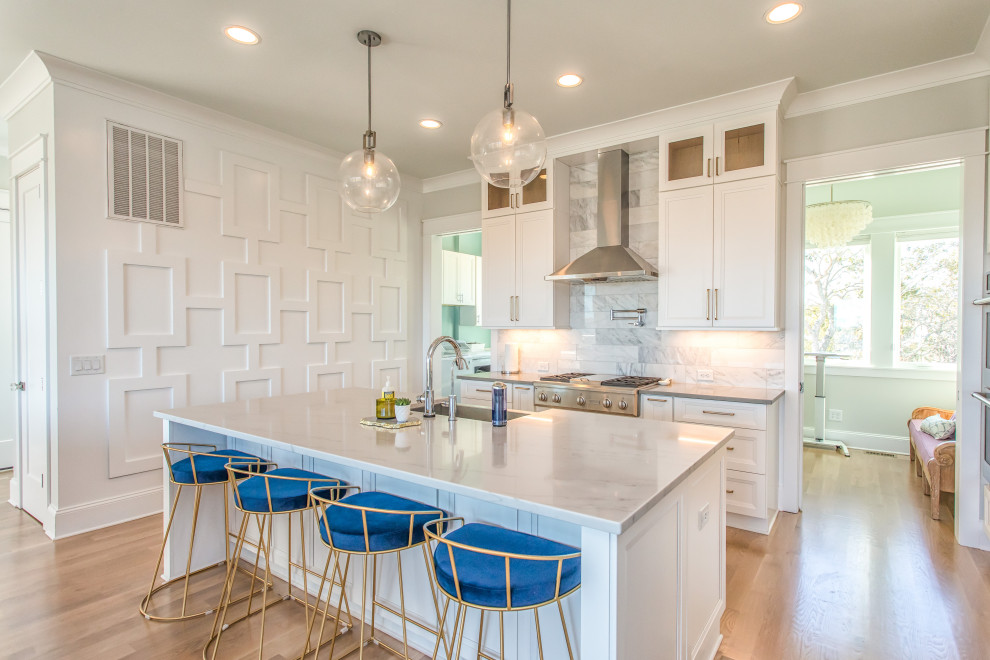 Large transitional l-shaped beige floor kitchen photo with an undermount sink, recessed-panel cabinets, white cabinets, gray backsplash, porcelain backsplash, stainless steel appliances, an island and gray countertops
