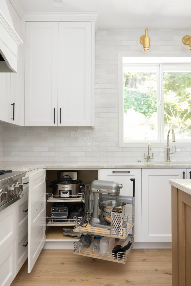 Large elegant light wood floor eat-in kitchen photo in Portland with a single-bowl sink, shaker cabinets, white cabinets, quartzite countertops, white backsplash, subway tile backsplash, stainless steel appliances, an island and beige countertops