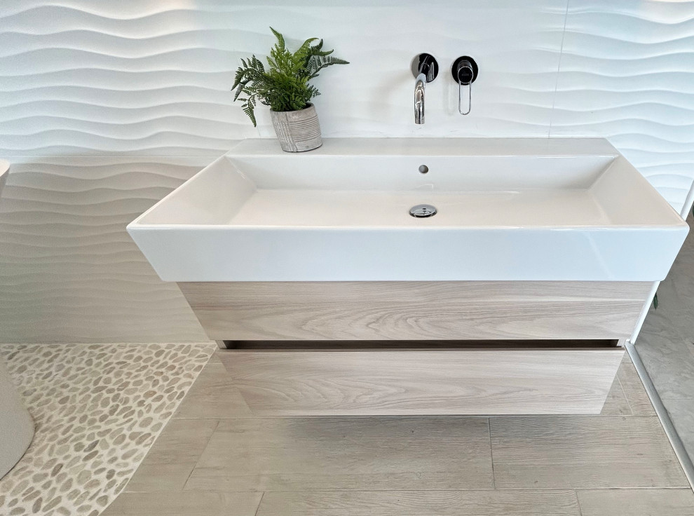 Aménagement d'une grande salle de bain principale scandinave en bois clair avec un placard à porte plane, un carrelage blanc, des carreaux de porcelaine, un mur blanc, un sol en galet, une grande vasque, un sol beige, meuble simple vasque et meuble-lavabo suspendu.