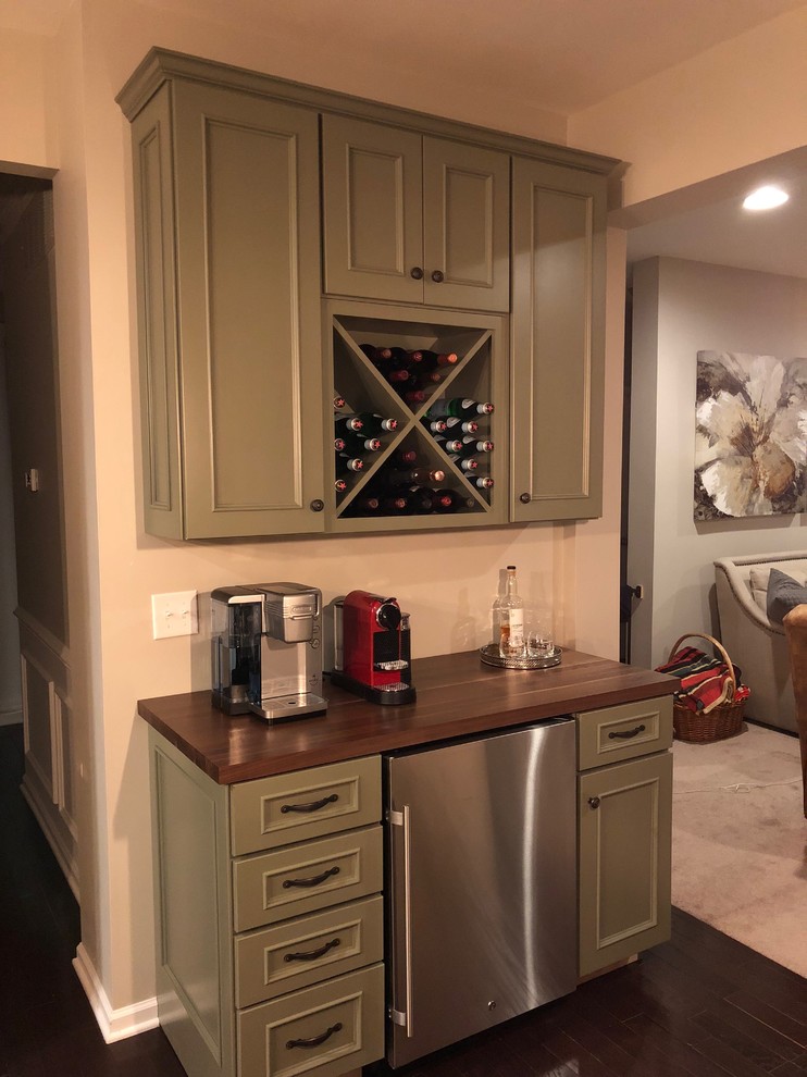 Small traditional single-wall home bar in Philadelphia with flat-panel cabinets, green cabinets, wood benchtops, grey splashback and brown benchtop.