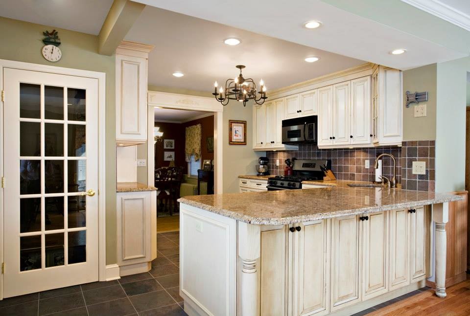 Mid-sized contemporary l-shaped eat-in kitchen in New York with an undermount sink, raised-panel cabinets, white cabinets, granite benchtops, grey splashback, ceramic splashback, stainless steel appliances, ceramic floors and a peninsula.