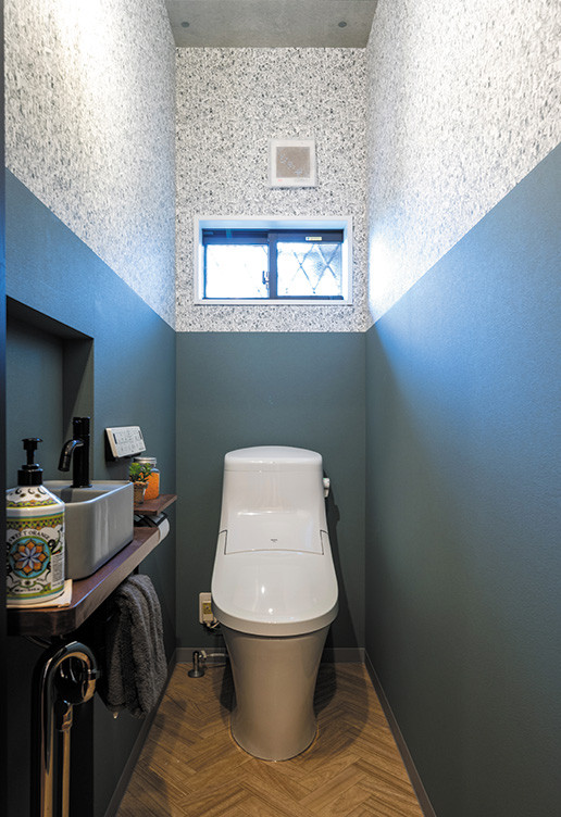 Small urban cloakroom in Other with dark wood cabinets, a one-piece toilet, multi-coloured walls, vinyl flooring, a vessel sink, wooden worktops, brown floors, a feature wall, a built in vanity unit, a wallpapered ceiling and wallpapered walls.