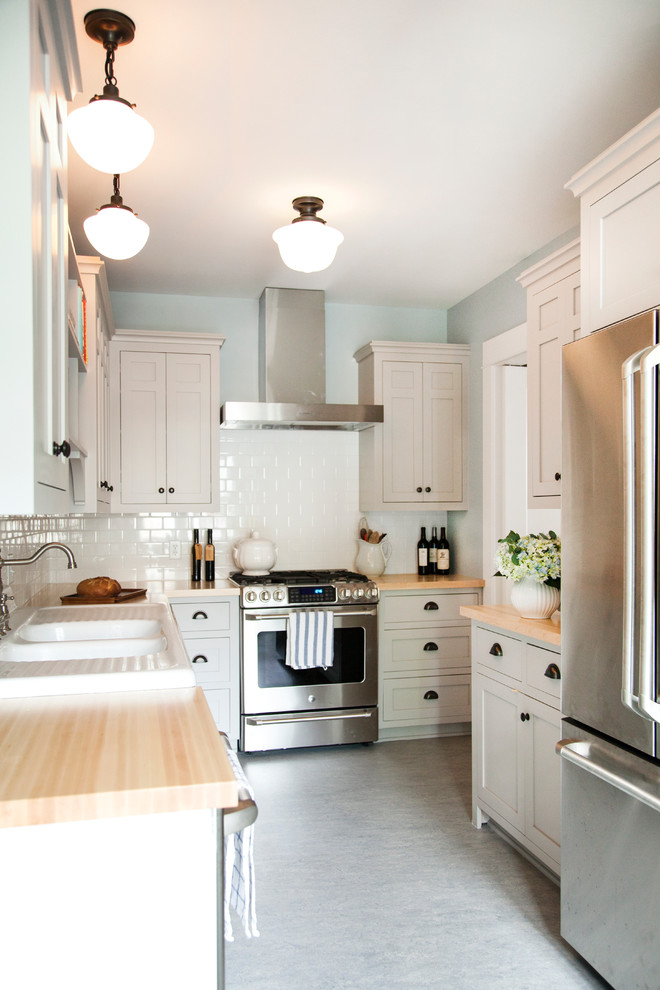 Inspiration for a small traditional l-shaped eat-in kitchen in Minneapolis with a double-bowl sink, recessed-panel cabinets, white cabinets, wood benchtops, white splashback, stainless steel appliances, linoleum floors and no island.