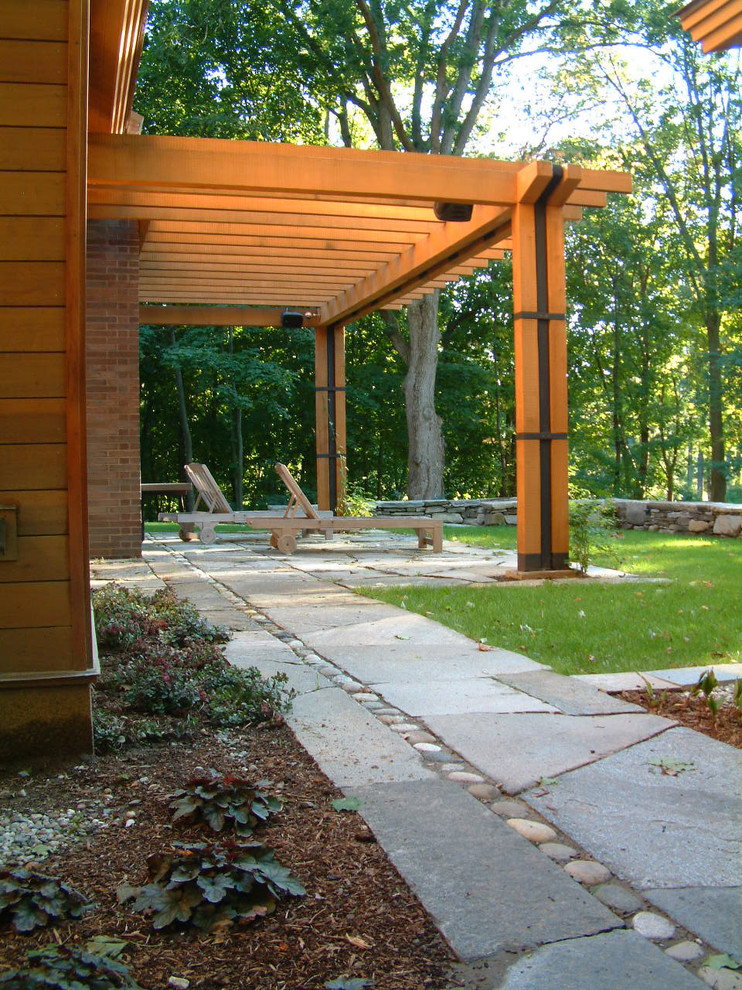 This is an example of a mid-sized country backyard patio in Burlington with a pergola and concrete pavers.