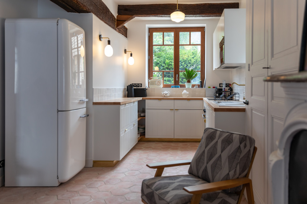 Inspiration for a mid-sized country u-shaped terra-cotta tile, pink floor and exposed beam open concept kitchen remodel in Le Havre with an undermount sink, beaded inset cabinets, white cabinets, wood countertops, white backsplash, paneled appliances, no island and beige countertops