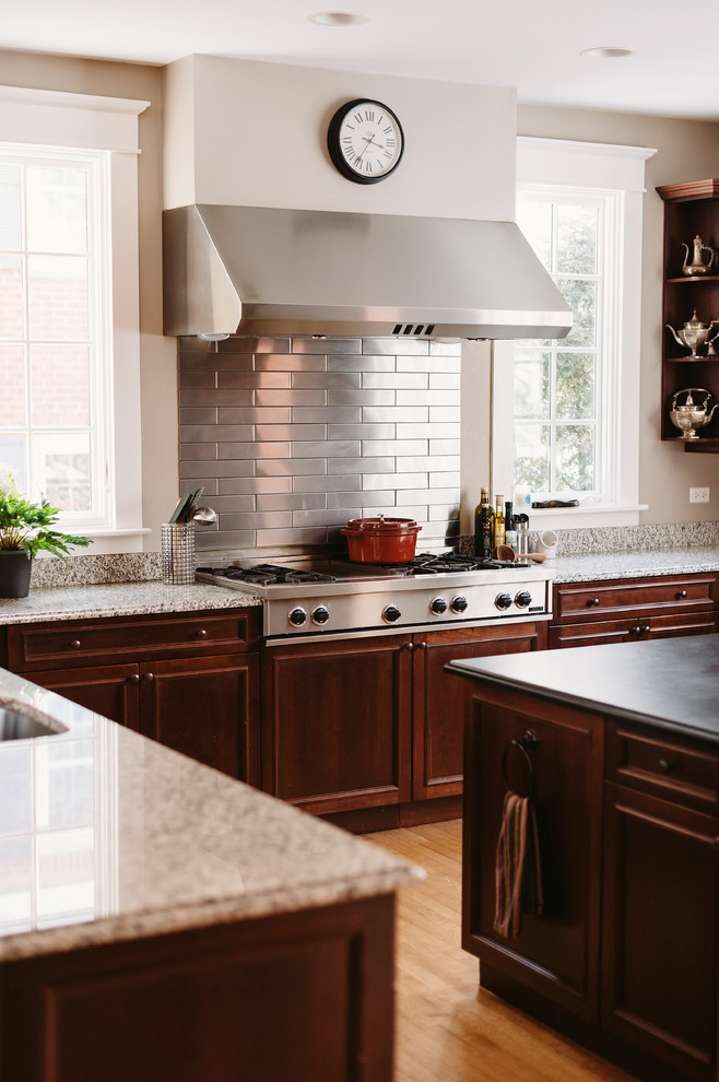 Example of a large transitional u-shaped medium tone wood floor eat-in kitchen design with recessed-panel cabinets, brown cabinets, granite countertops, metallic backsplash, subway tile backsplash, stainless steel appliances and gray walls
