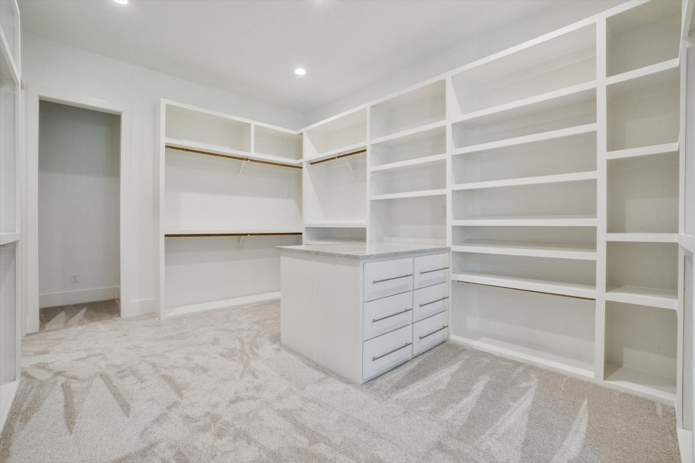 Inspiration for a large traditional gender neutral walk-in wardrobe in Dallas with flat-panel cabinets, white cabinets, carpet and beige floors.