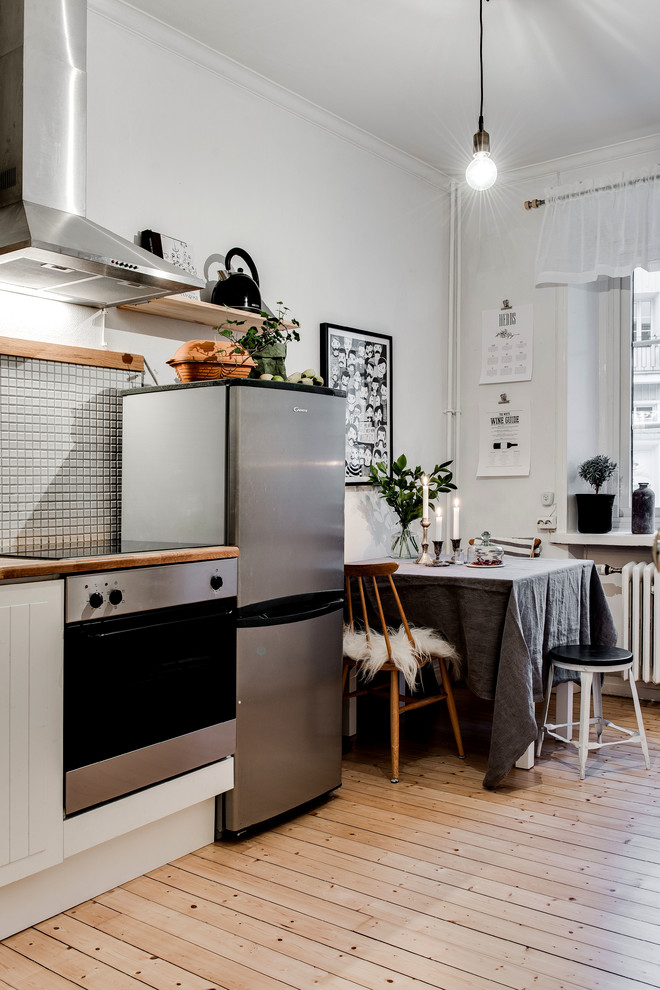 Inspiration for a small scandinavian separate kitchen in Gothenburg with wood benchtops, grey splashback, stainless steel appliances, light hardwood floors and no island.