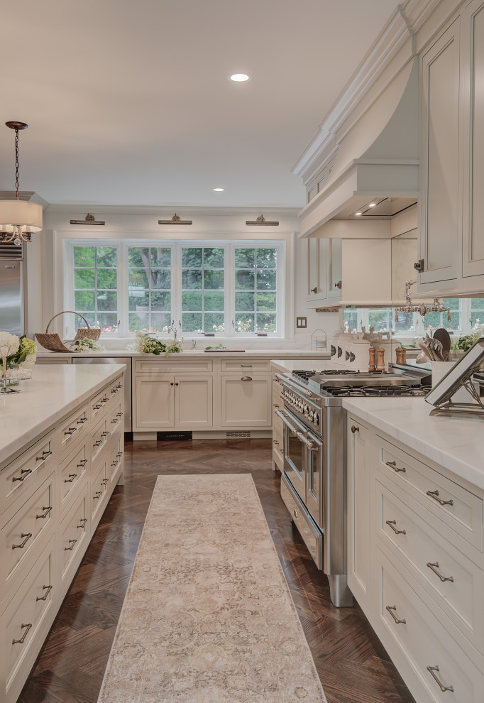 Inspiration for a huge timeless u-shaped medium tone wood floor and brown floor kitchen remodel in New York with an undermount sink, beaded inset cabinets, beige cabinets, marble countertops, mirror backsplash, stainless steel appliances, an island and white countertops