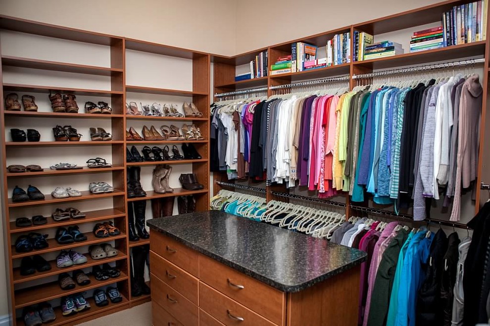 Mid-sized traditional women's walk-in wardrobe in Denver with open cabinets, medium wood cabinets and carpet.
