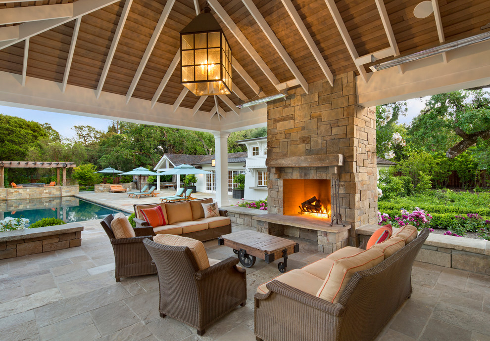 This is an example of a traditional backyard patio in San Francisco with natural stone pavers, a gazebo/cabana and with fireplace.