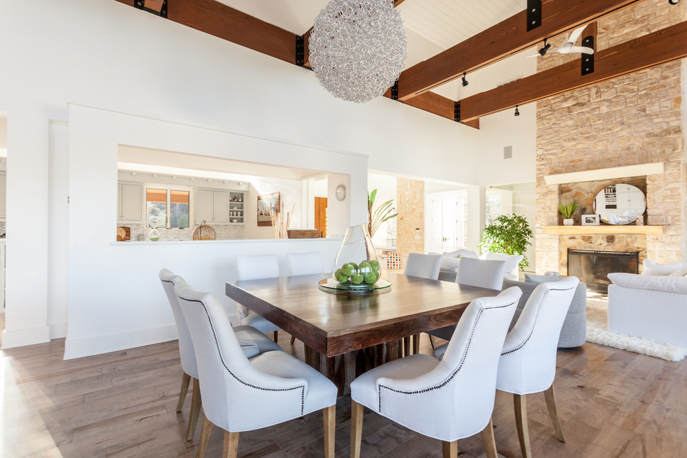 Design ideas for a contemporary dining room in Austin with white walls, light hardwood floors, a standard fireplace and a stone fireplace surround.