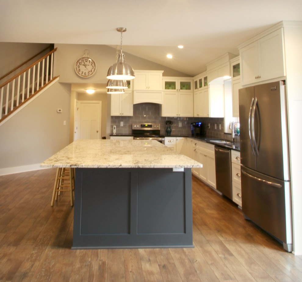 Inspiration for a large transitional l-shaped eat-in kitchen in Minneapolis with shaker cabinets, white cabinets, granite benchtops, brown splashback, ceramic splashback, stainless steel appliances, dark hardwood floors, with island and brown floor.