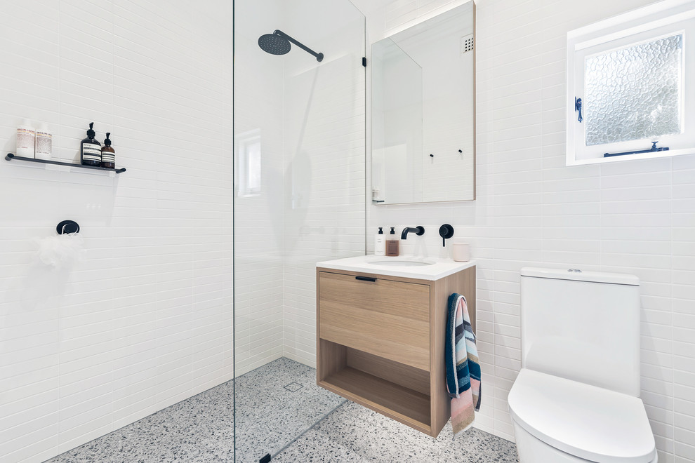 This is an example of a small scandinavian 3/4 bathroom in Perth with flat-panel cabinets, light wood cabinets, an open shower, a one-piece toilet, white tile, porcelain tile, white walls, porcelain floors, an undermount sink, engineered quartz benchtops, grey floor, an open shower and white benchtops.