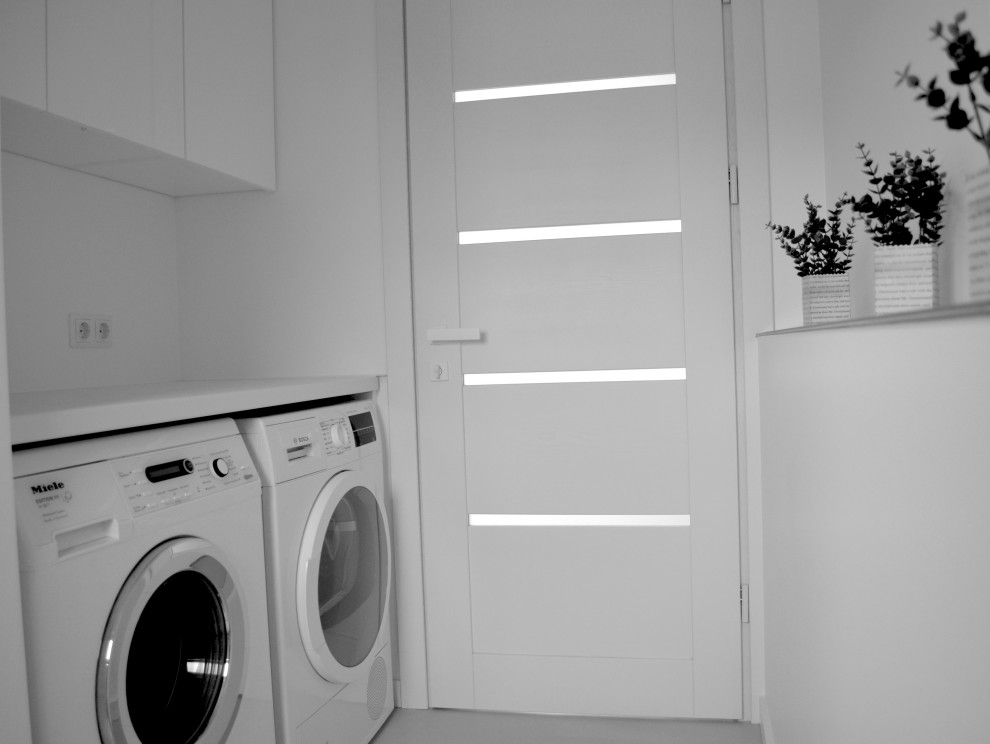 Photo of a small modern single-wall laundry cupboard in Other with white walls, a side-by-side washer and dryer and grey floor.