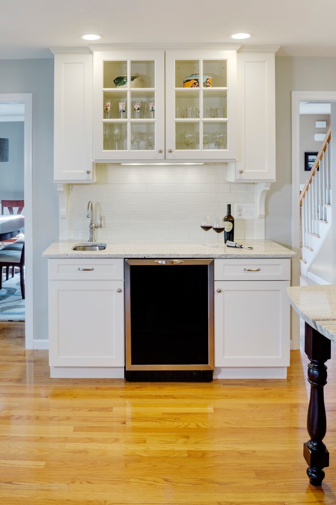 Inspiration for a transitional l-shaped kitchen in Boston with an undermount sink, shaker cabinets, white cabinets, granite benchtops, white splashback, subway tile splashback, stainless steel appliances, light hardwood floors and with island.