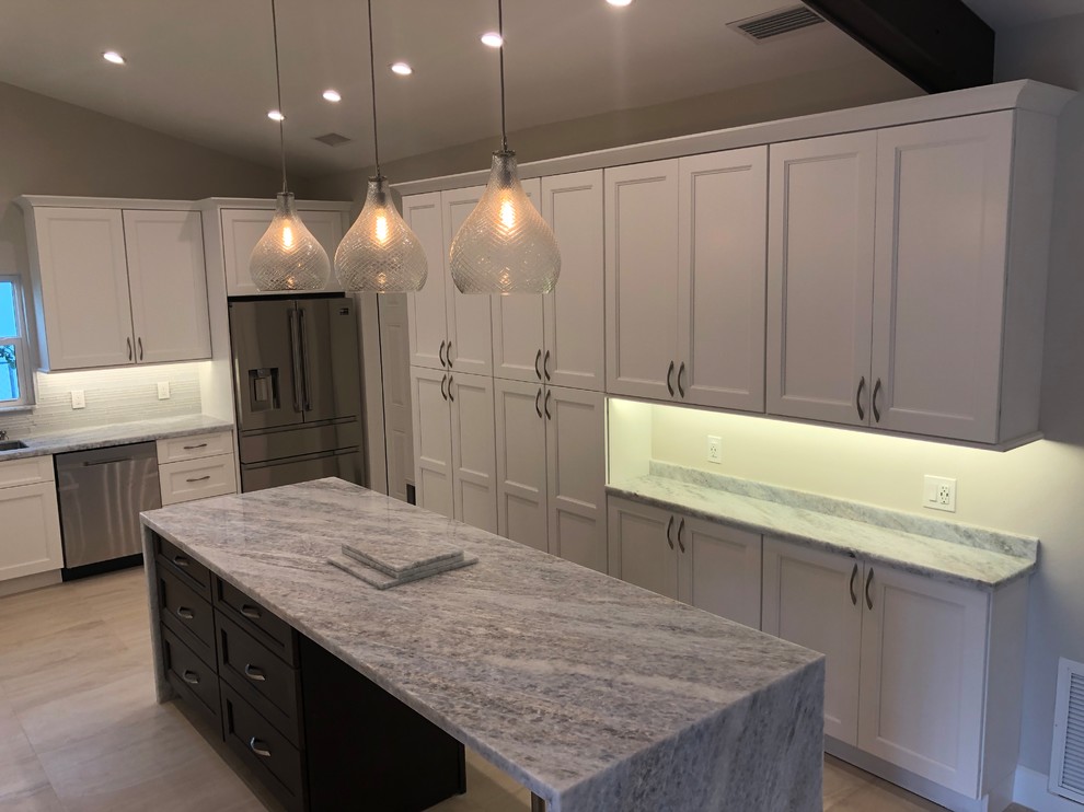 Inspiration for a mid-sized transitional u-shaped beige floor kitchen remodel in Miami with an undermount sink, recessed-panel cabinets, white cabinets, gray backsplash, glass tile backsplash, stainless steel appliances, an island and gray countertops