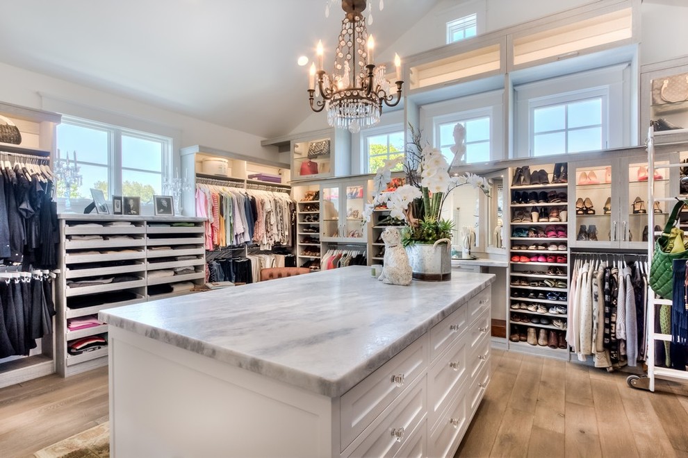 Inspiration for an expansive country women's walk-in wardrobe in Orange County with open cabinets, white cabinets and light hardwood floors.