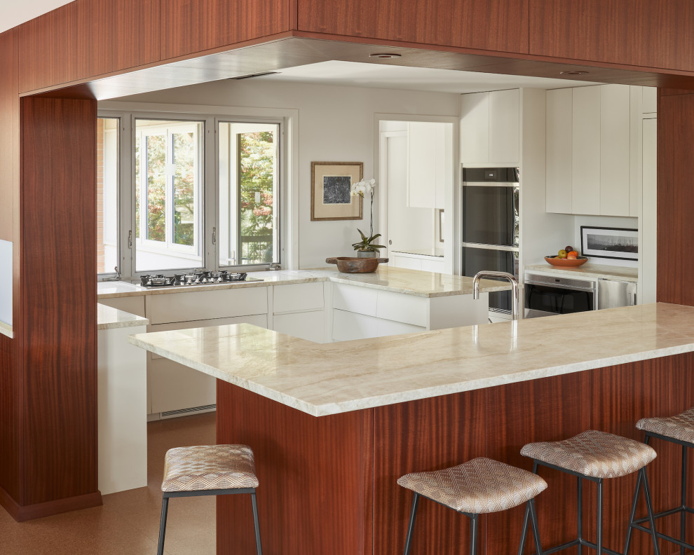Photo of a small midcentury u-shaped kitchen in Austin with flat-panel cabinets, white cabinets, white splashback, stainless steel appliances, cork floors, brown floor, beige benchtop and a peninsula.
