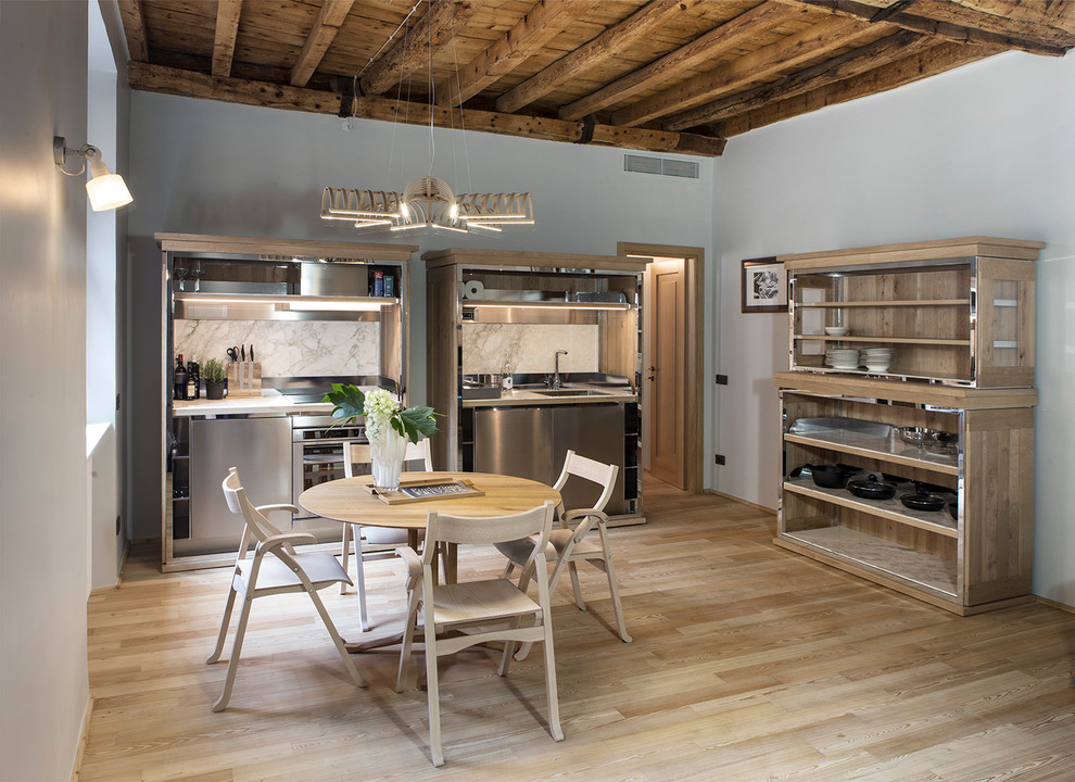 Beach style kitchen/dining combo in Milan with blue walls and light hardwood floors.