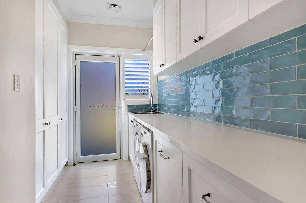 This is an example of a large contemporary galley dedicated laundry room in Sydney with a single-bowl sink, shaker cabinets, white cabinets, quartz benchtops, beige walls, porcelain floors, a side-by-side washer and dryer, beige floor and white benchtop.