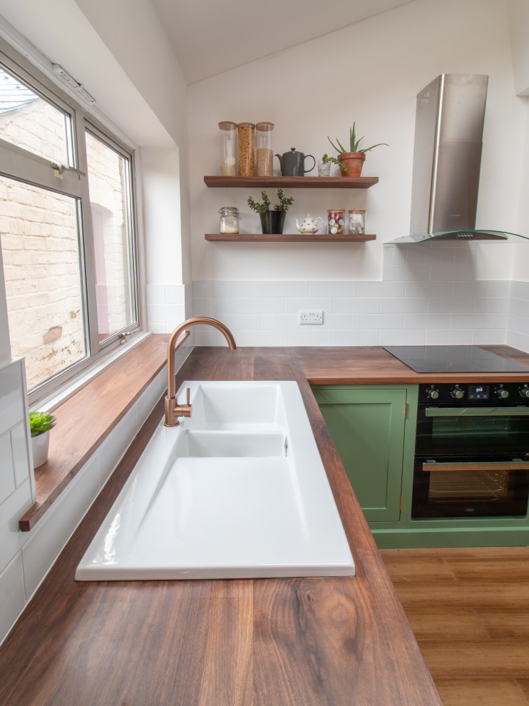 Photo of a mid-sized modern l-shaped eat-in kitchen in Cheshire with a drop-in sink, shaker cabinets, green cabinets, wood benchtops, with island, brown benchtop, white splashback, subway tile splashback, panelled appliances, dark hardwood floors and brown floor.