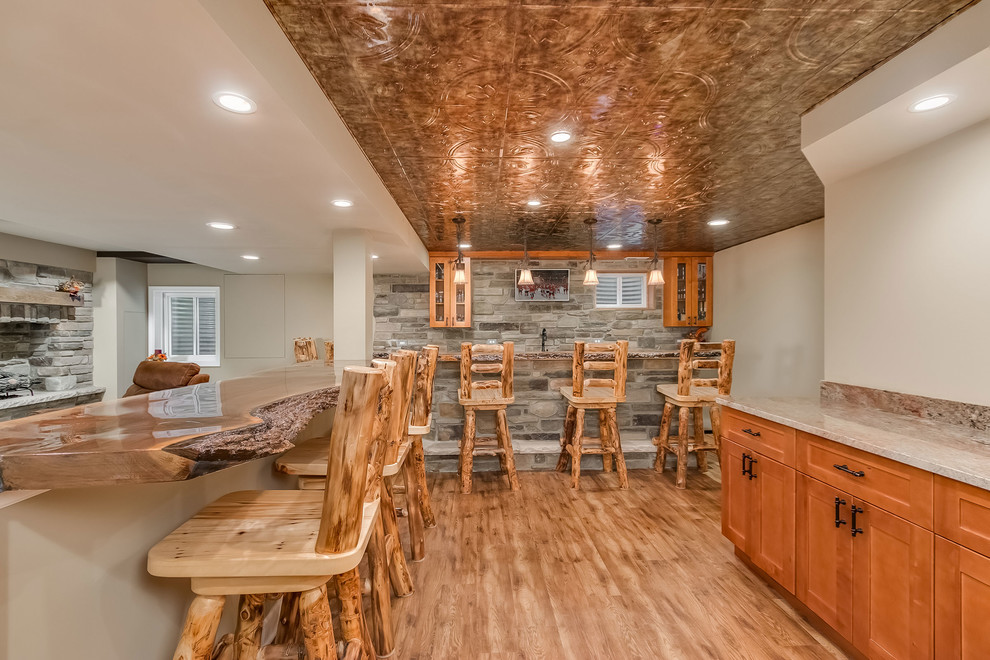 Inspiration for a large rustic look-out medium tone wood floor and beige floor basement remodel in Chicago with gray walls, a standard fireplace and a stone fireplace