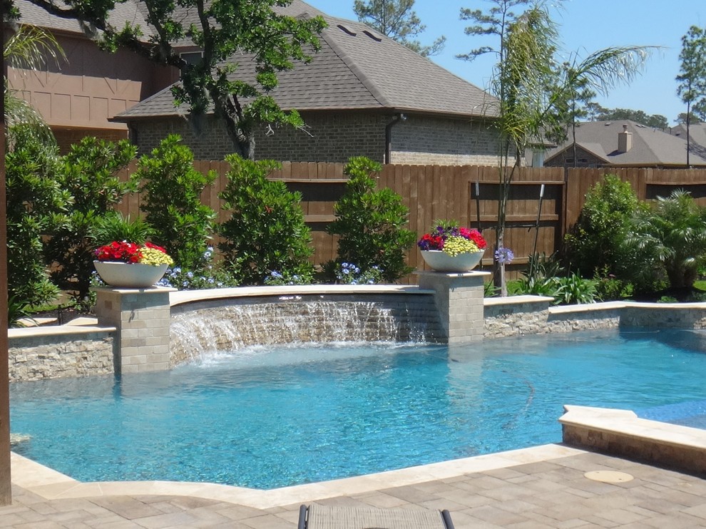 Photo of a large traditional backyard custom-shaped lap pool in Houston with a water feature and brick pavers.