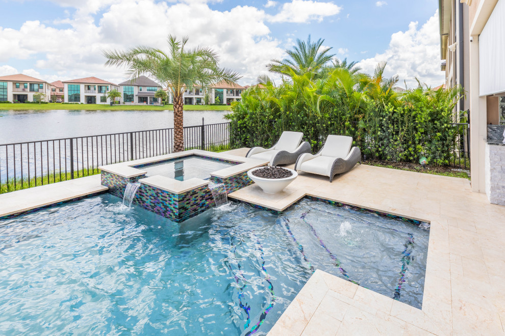 Photo of a mid-sized tropical backyard rectangular lap pool in Miami with a hot tub and natural stone pavers.