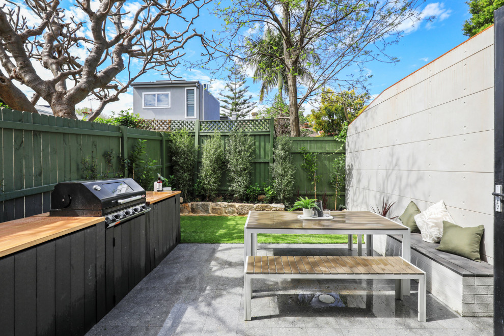 Contemporary patio in Sydney with natural stone pavers and no cover.