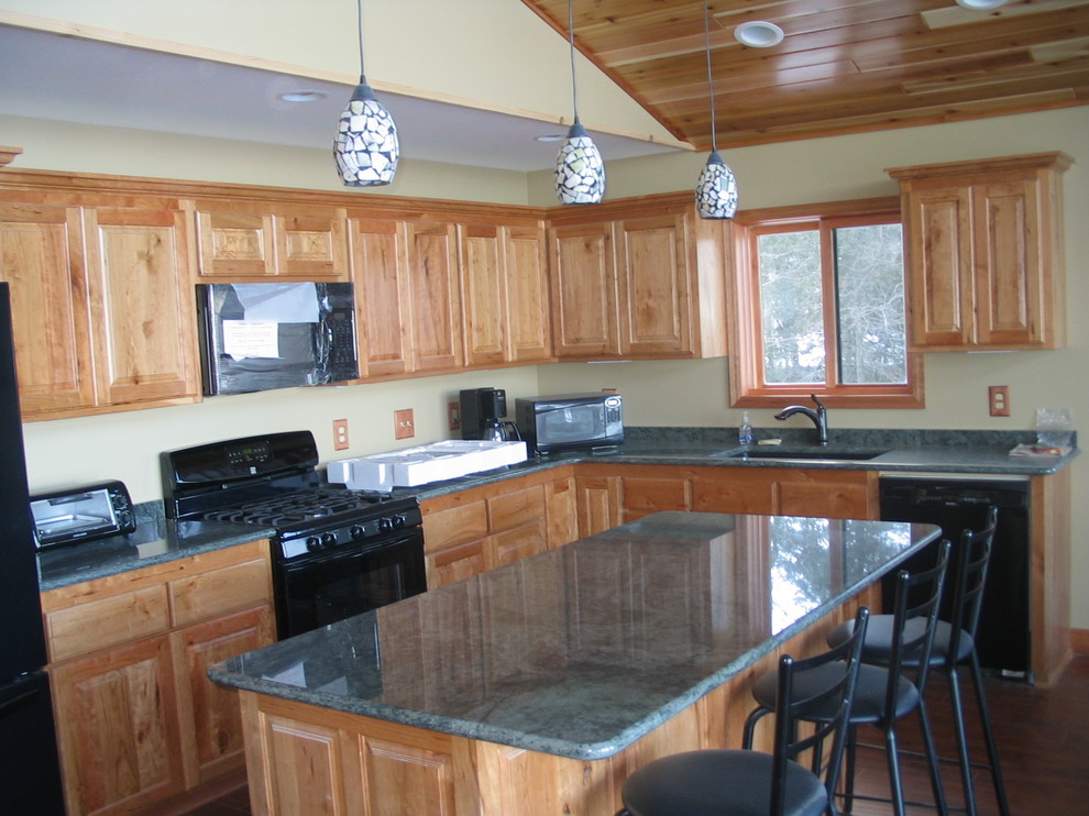 Mid-sized mountain style l-shaped light wood floor and beige floor enclosed kitchen photo with a double-bowl sink, raised-panel cabinets, light wood cabinets, granite countertops, stainless steel appliances and an island