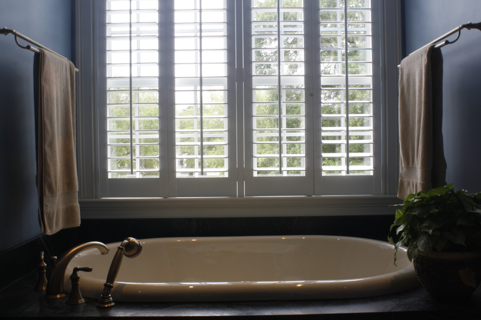 This is an example of a large traditional master bathroom in Charleston with a drop-in tub and blue walls.