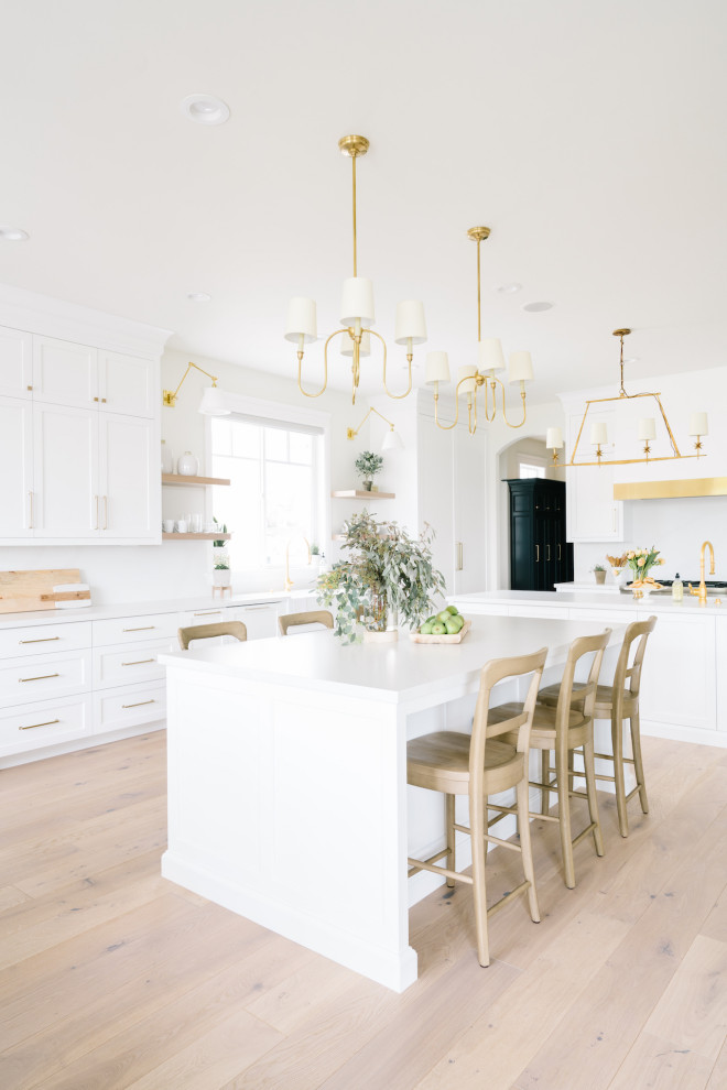 Transitional kitchen in Salt Lake City with a farmhouse sink, shaker cabinets, white cabinets, white splashback, panelled appliances, multiple islands and white benchtop.