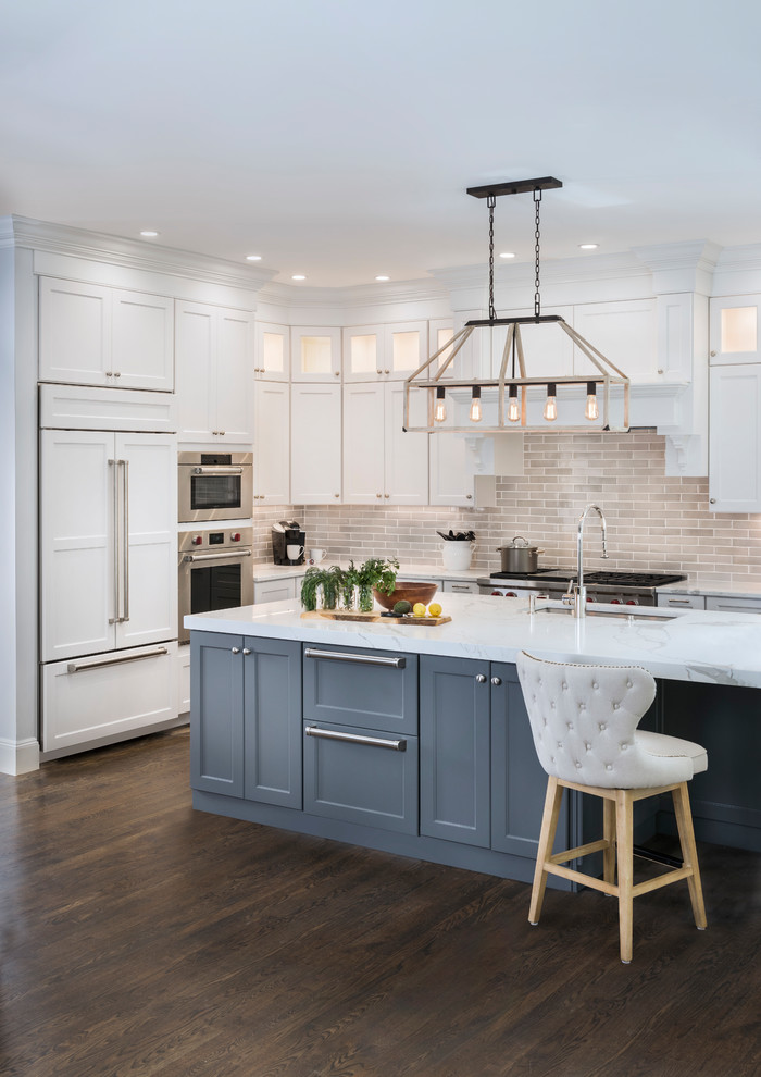 Example of a large transitional l-shaped medium tone wood floor and brown floor eat-in kitchen design in Boston with an undermount sink, recessed-panel cabinets, white cabinets, marble countertops, gray backsplash, ceramic backsplash, stainless steel appliances and an island
