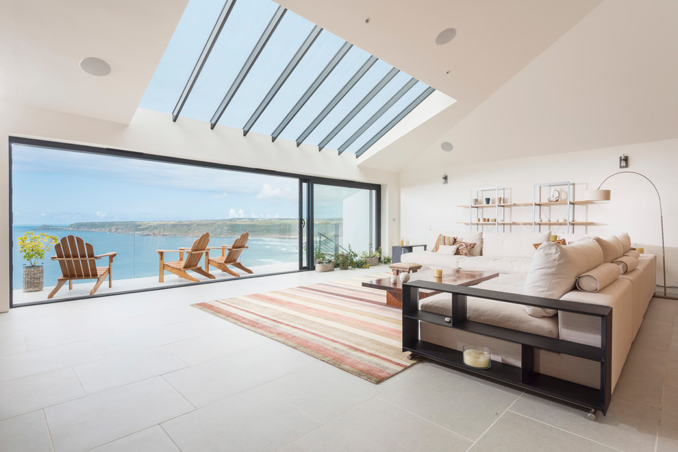This is an example of a contemporary open concept living room in Cornwall with white walls.