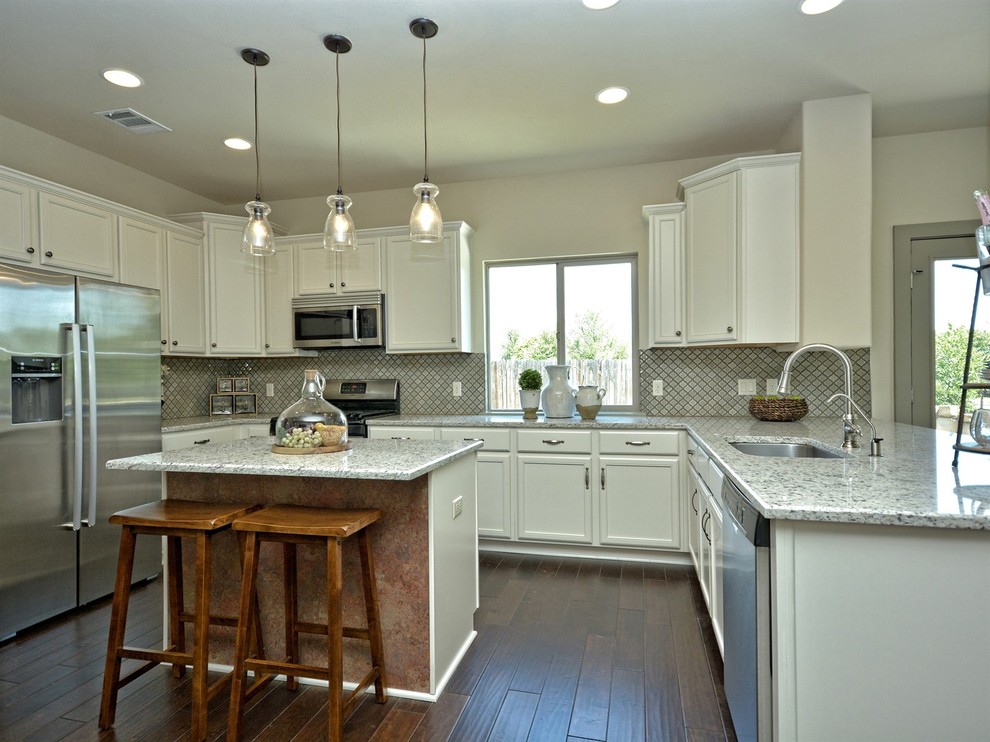 Inspiration for a mid-sized country u-shaped kitchen in Austin with an undermount sink, recessed-panel cabinets, white cabinets, granite benchtops, green splashback, porcelain splashback, stainless steel appliances, dark hardwood floors and with island.