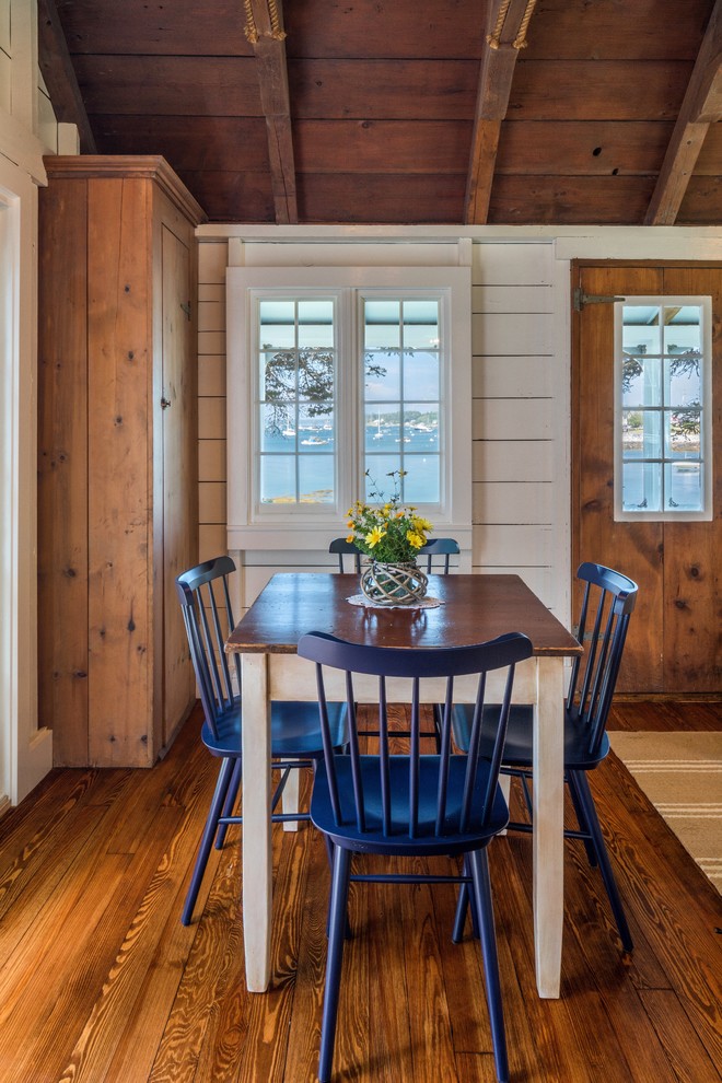 This is an example of a beach style dining room in Portland Maine with white walls, medium hardwood floors and brown floor.