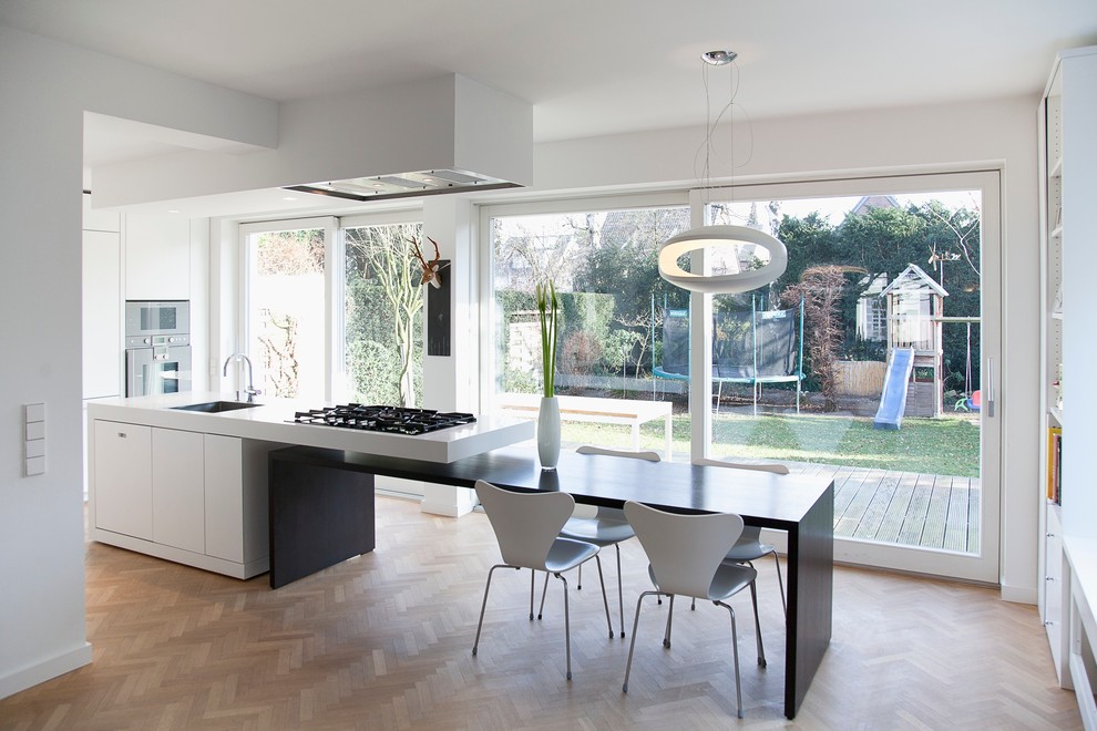Photo of a mid-sized contemporary kitchen/dining combo in Cologne with white walls and light hardwood floors.